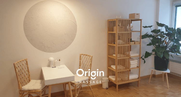 Heller Warte- und Beratungsbereich von Origin Massage Basel mit Tisch, Stuehlen und Holzregal.